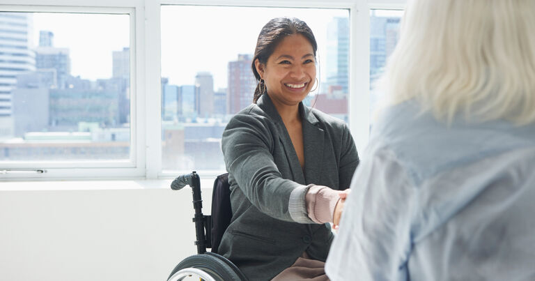 A teacher job candidate shakes the hand of her interviewer during a job interview.